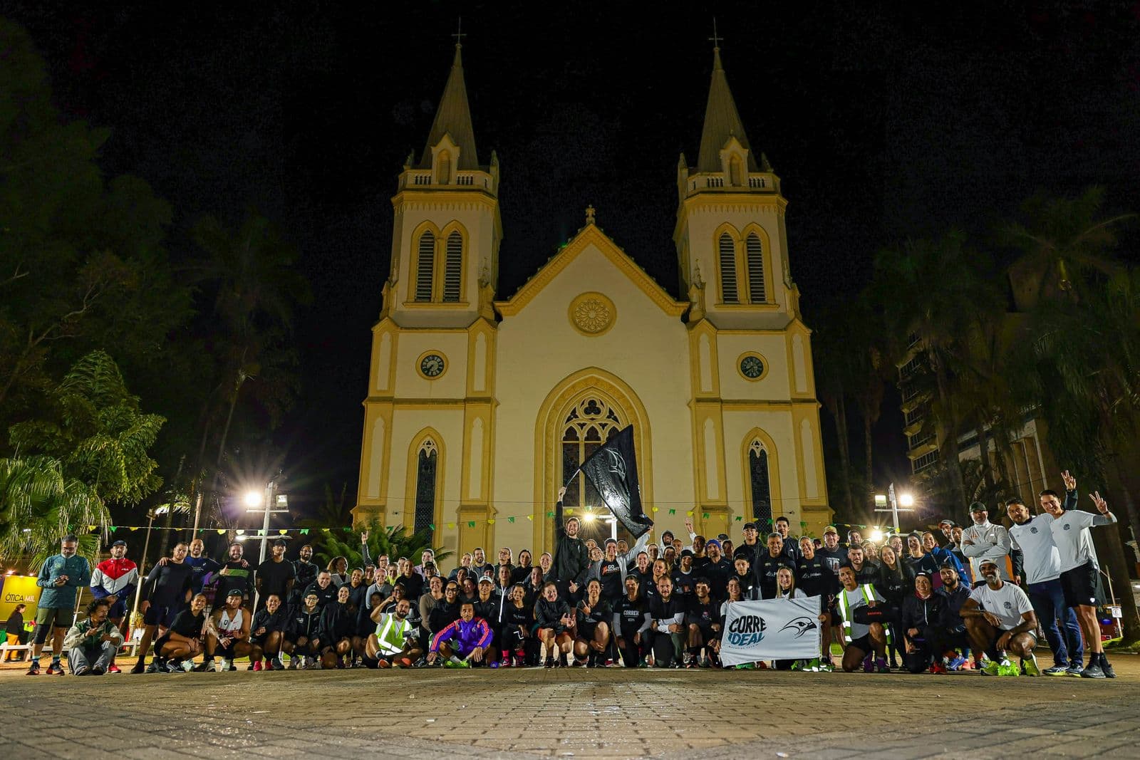 Corredores do Corre Ideal com bandeiras em frente à Igreja Matriz de Jundiaí à noite